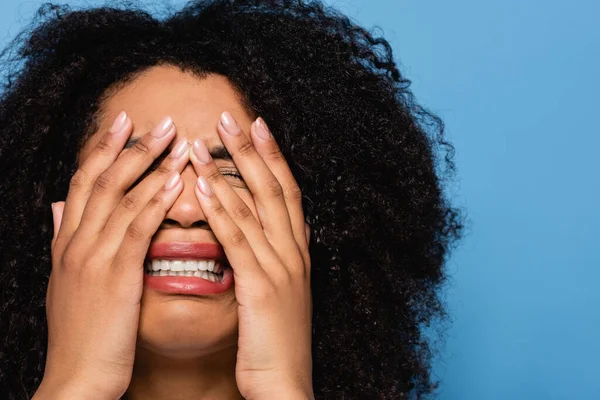 Aufgebracht afrikanisch-amerikanische Frau verdeckt Gesicht mit Händen, während weint isoliert auf blau — Stockfoto