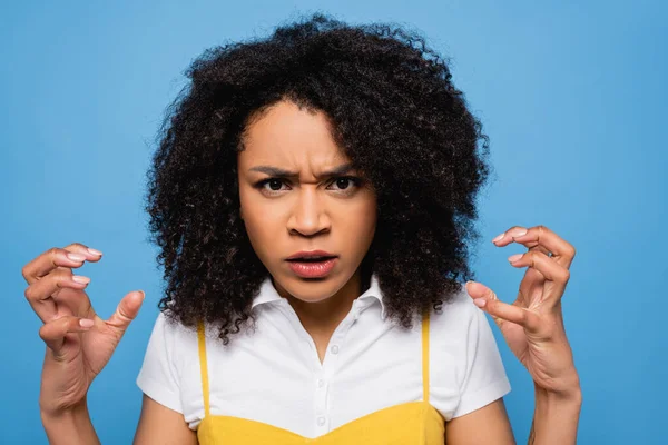 Irritated african american woman showing scary gesture at camera isolated on blue — Stock Photo