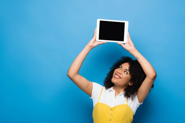 Happy african american woman holding digital tablet with blank screen on blue — Stock Photo