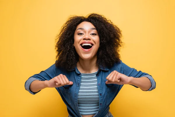 Amazed african american woman pointing with thumbs at herself isolated on yellow — Stock Photo