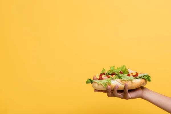 Vue recadrée de femme afro-américaine avec délicieux hot dog isolé sur jaune — Photo de stock