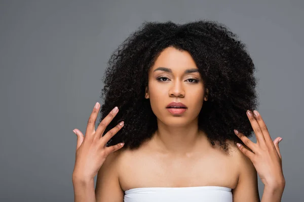 Pretty african american woman with perfect skin and natural makeup looking at camera isolated on grey — Stock Photo