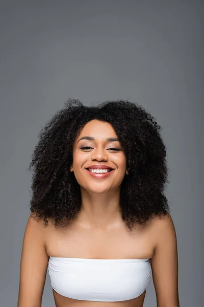 Mulher americana africana alegre com pele perfeita sorrindo para a câmera isolada em cinza — Fotografia de Stock