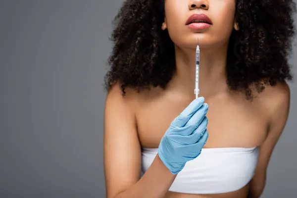 Vue partielle de femme afro-américaine floue en gant de latex tenant injection de beauté isolé sur gris — Photo de stock