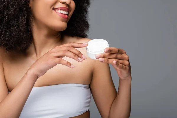 Cropped view of african american woman in white top holding cosmetic cream isolated on grey — Stock Photo