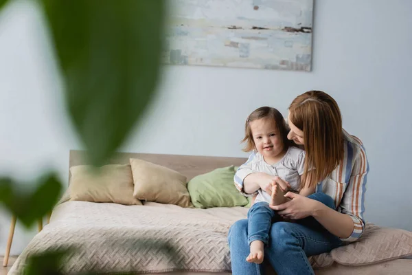 Mutter umarmt kleine Tochter mit Down-Syndrom im Schlafzimmer — Stockfoto