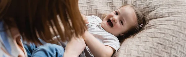 Mãe desfocada brincando com a filha da criança com síndrome de down na cama, banner — Fotografia de Stock