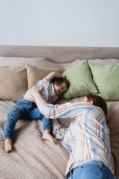 Woman lying near baby daughter with down syndrome on bed at home — Stock Photo