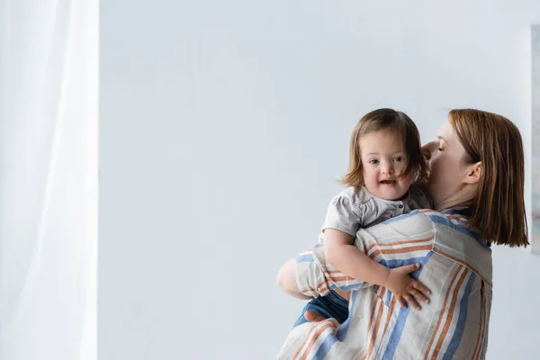 Woman holding child with down syndrome at home — Stock Photo