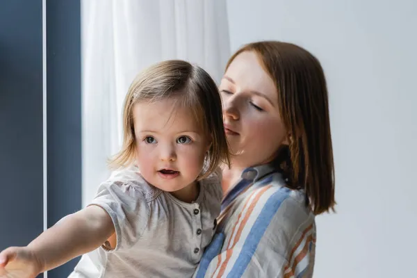 Blurred mother looking at daughter with down syndrome at home — Stock Photo