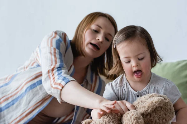 Mother and kid with down syndrome playing with soft toy at home — Stock Photo