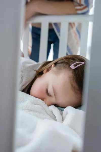 Child with down syndrome sleeping in baby crib near mother — Stock Photo