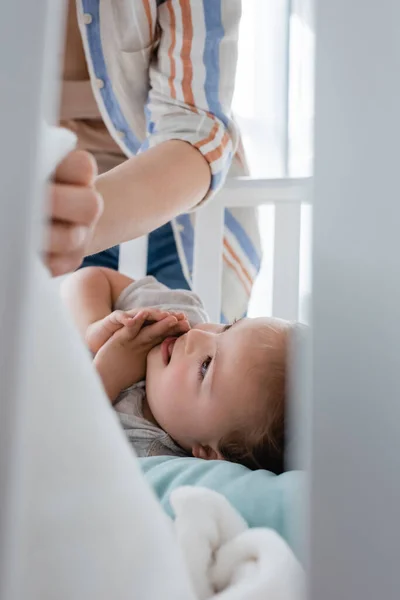 Lächelndes Kind mit Down-Syndrom liegt in Babybett neben Mutter — Stockfoto