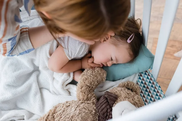 Overhead view of parent touching daughter with down syndrome in baby crib — Stock Photo