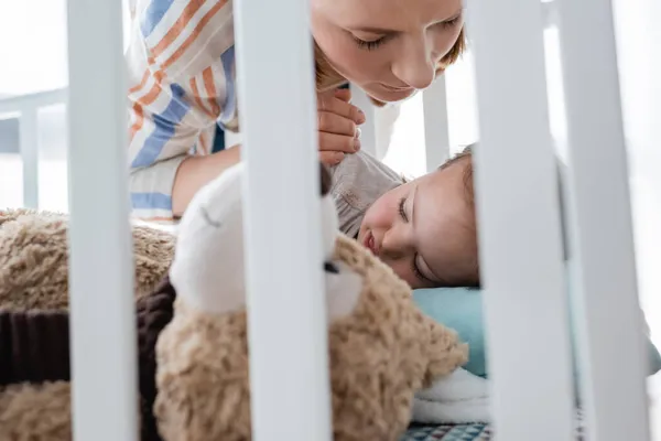 Mãe olhando para bebê dormindo com síndrome de down no berço do bebê — Fotografia de Stock