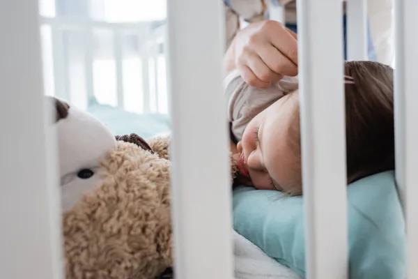 Padre tocando a la hija dormida con síndrome de Down en la cuna en casa - foto de stock