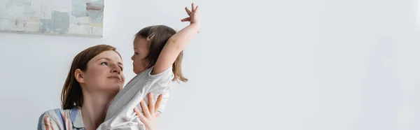 Родитель держит дочь с синдромом Дауна дома, баннер — стоковое фото
