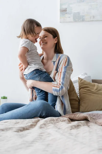 Mujer feliz mirando a la hija con síndrome de Down que sobresale de la lengua - foto de stock