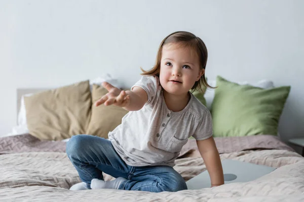 Ragazza del bambino con sindrome di Down guardando lontano vicino laptop sul letto — Foto stock