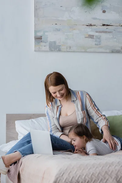 Glückliche Freiberuflerin berührt Kleinkind mit Down-Syndrom im Bett — Stockfoto