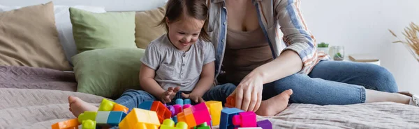 Madre e bambino con sindrome di Down giocando mattoni sul letto, striscione — Foto stock