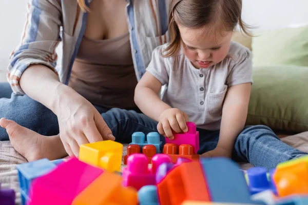 Building blocks near toddler kid with down syndrome and mother on bed — Stock Photo
