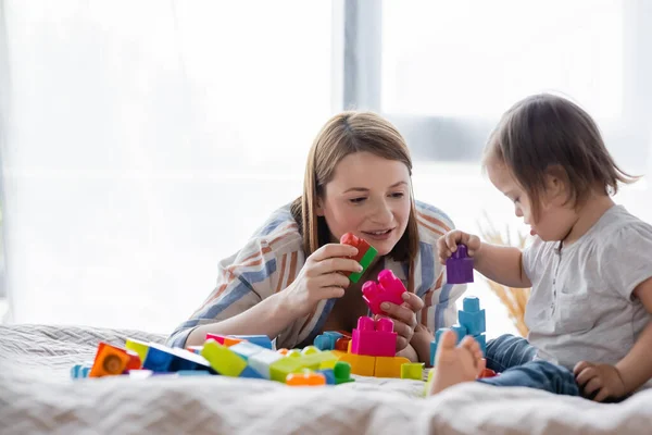 Femme positive jouant blocs de construction avec fille avec le syndrome du duvet à la maison — Photo de stock