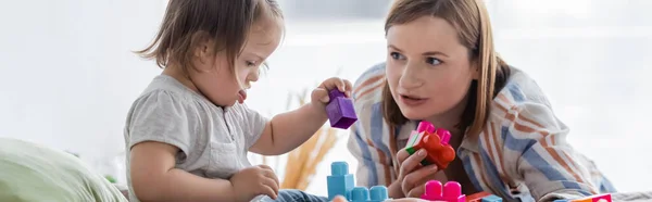 Madre hablando con su hija con síndrome de Down jugando bloques de construcción en casa, pancarta - foto de stock