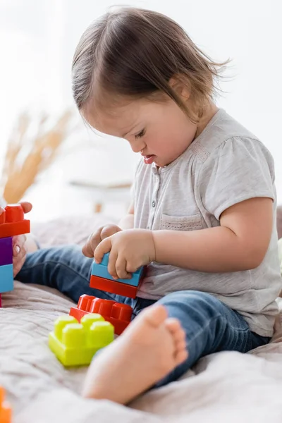 Toddler girl with down syndrome playing building blocks near parent at home — Stock Photo
