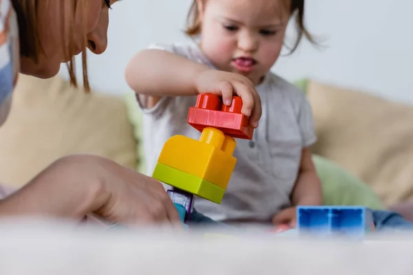 Blurred kid with down syndrome playing building blocks near parent at home — Stock Photo
