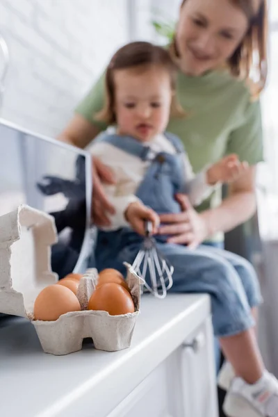 Ovos perto de mãe e filha no fundo borrado na cozinha — Fotografia de Stock