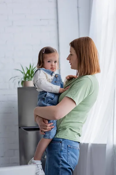 Mujer sosteniendo bebé hija con síndrome de Down en casa - foto de stock