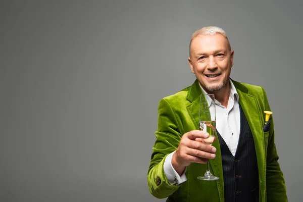 Smiling man in jacket holding champagne and looking at camera isolated on grey — Stock Photo