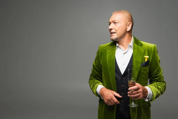 Mature man in formal wear holding champagne and looking away isolated on grey — Stock Photo