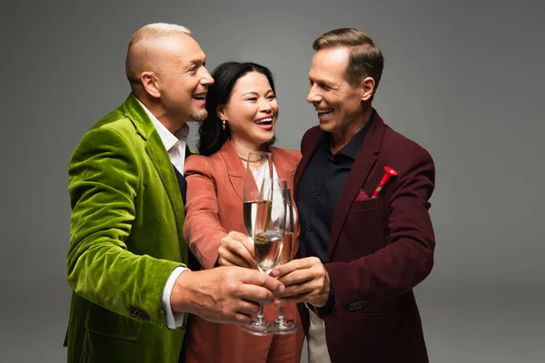 Feliz interracial amigos tostando champán durante la fiesta aislado en gris — Stock Photo