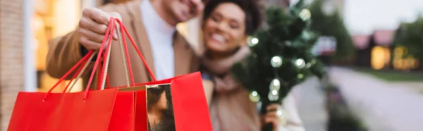 Blurred interracial couple with christmas shopping bags, banner — Stock Photo