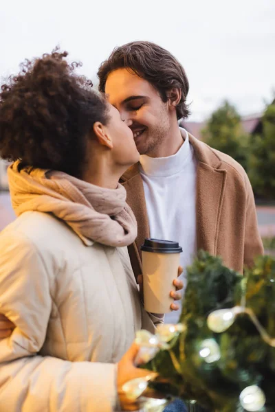 Heureux couple multiethnique avec les yeux fermés baisers en plein air — Photo de stock