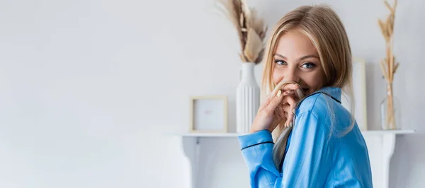 Feliz joven mujer sonriendo y cubriendo la boca con pelo, pancarta - foto de stock