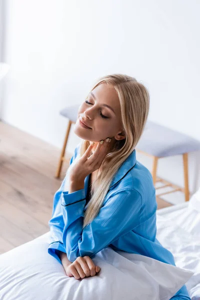 Vista de ángulo alto de la joven alegre sentada en la cama - foto de stock