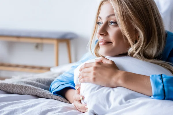 Happy blonde woman lying on pillow in bedroom — Stock Photo