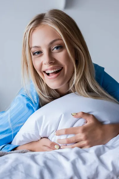 Femme blonde étonnée couchée sur l'oreiller dans la chambre — Photo de stock