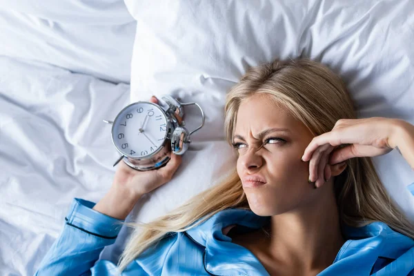 Vista superior de la mujer disgustada sosteniendo reloj despertador retro - foto de stock