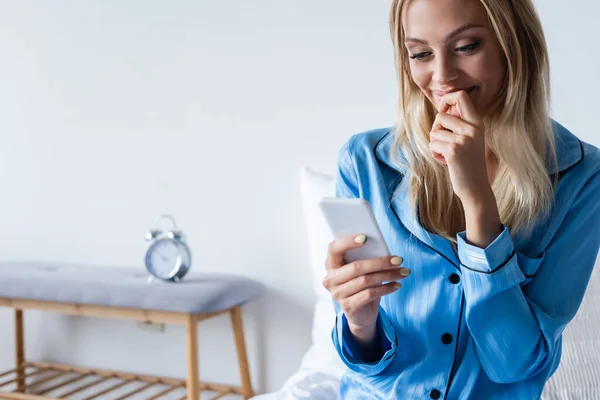 Mulher feliz em pijama falando no smartphone no quarto — Fotografia de Stock
