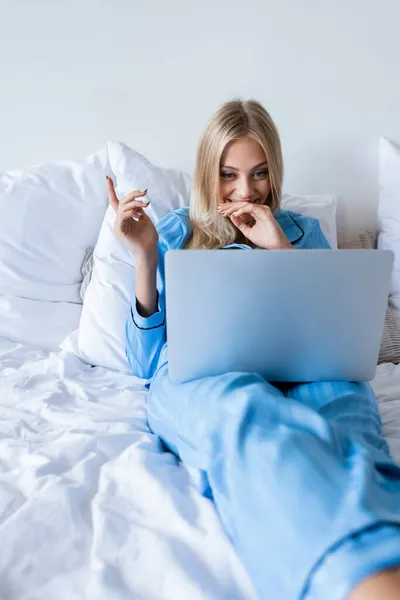 Jovem alegre em pijama assistindo filme de comédia no laptop no quarto — Fotografia de Stock