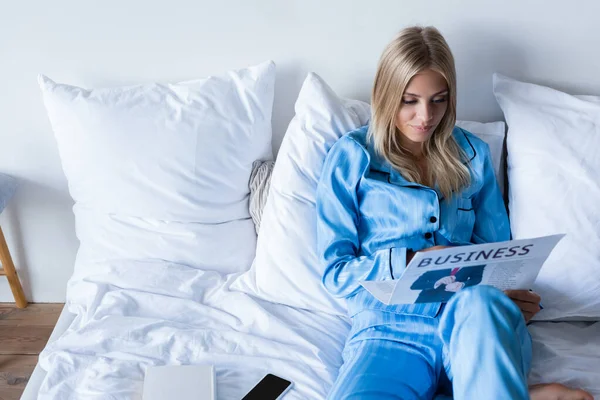 Blick aus der Vogelperspektive auf junge Frau im Pyjama, die Wirtschaftszeitung liest — Stockfoto