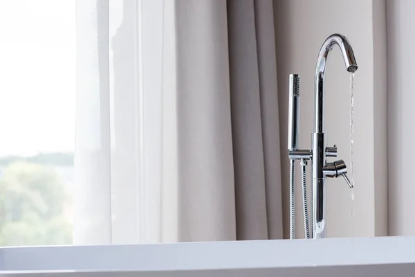 Water running from faucet into modern bathtub — Stock Photo