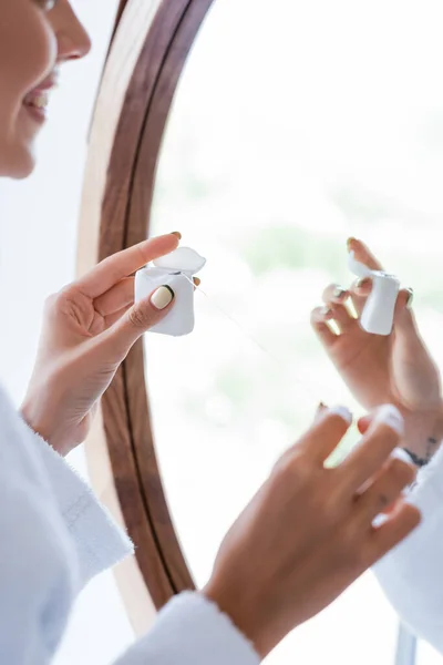 Cropped view of cheerful woman holding dental floss near mirror — Stock Photo