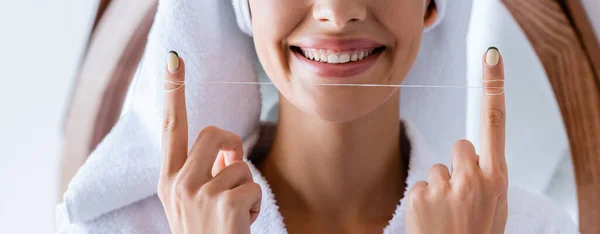 Partial view of happy woman holding dental floss in bathroom, banner — Stock Photo