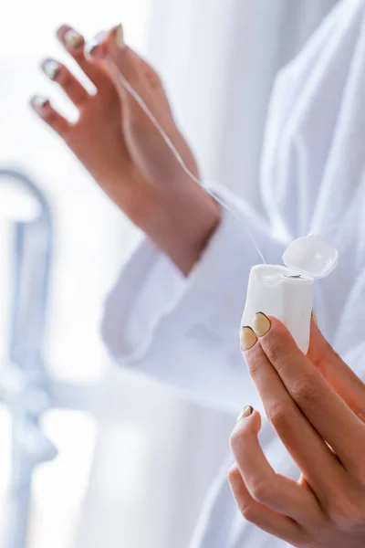 Partial view of young woman holding dental floss in bathroom — Stock Photo