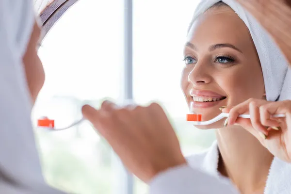 Mulher alegre escovando dentes e olhando para o espelho — Fotografia de Stock